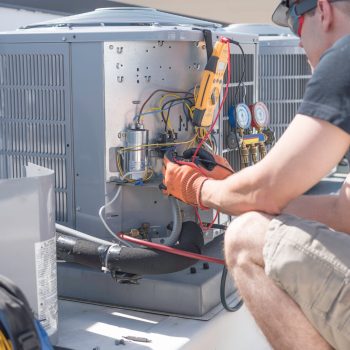 HVAC technician working on controls of air conditioner
